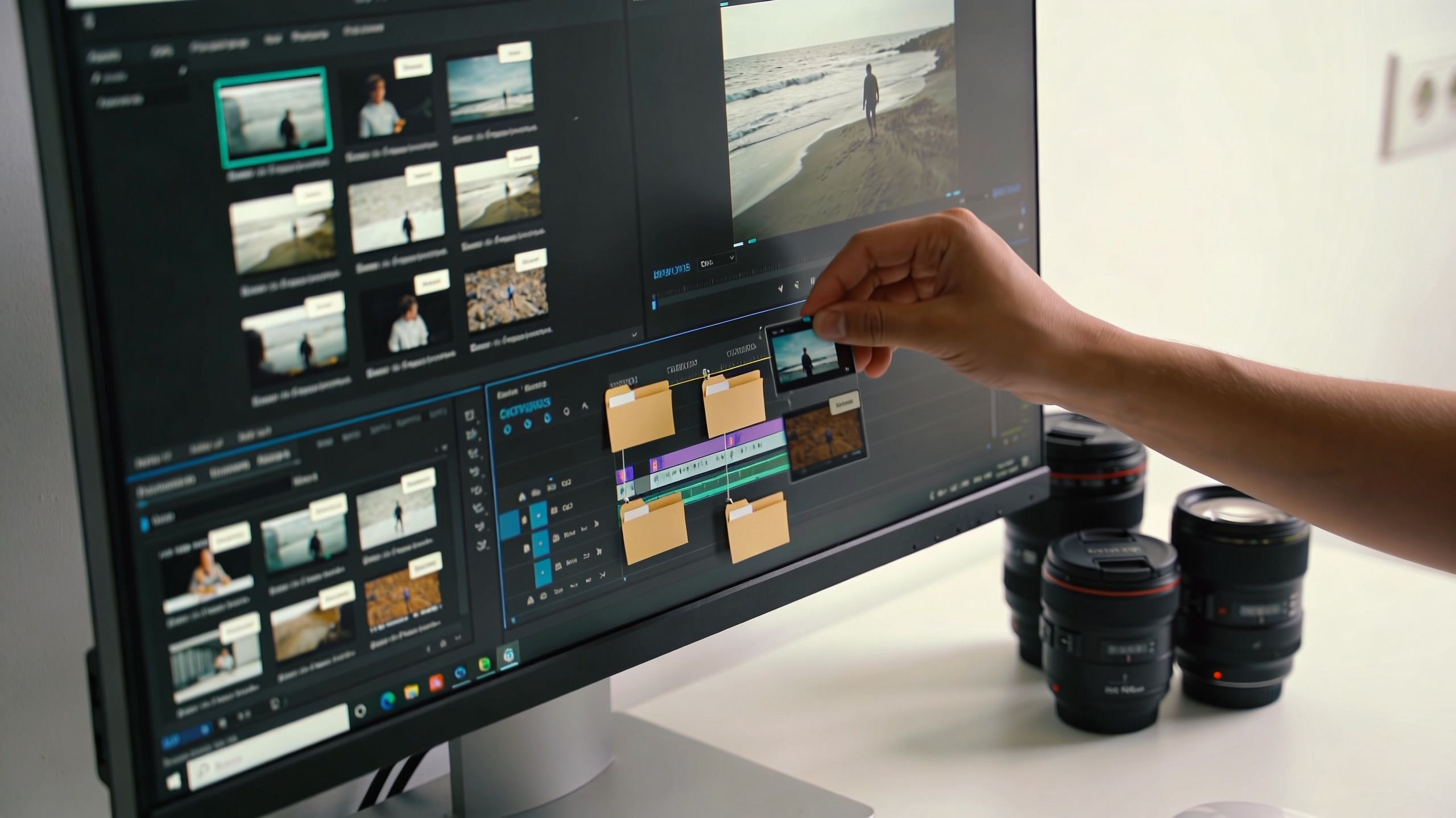 A video editor using computer software to edit professional film footage with camera lenses on the desk